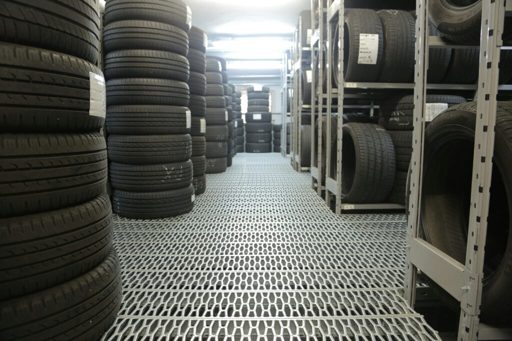 Rows of stacked tires in an indoor industrial warehouse for storage.