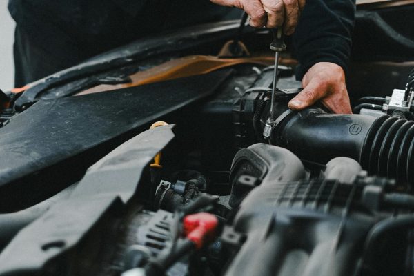 Detailed shot of mechanic working on a car engine showing hands and tools.